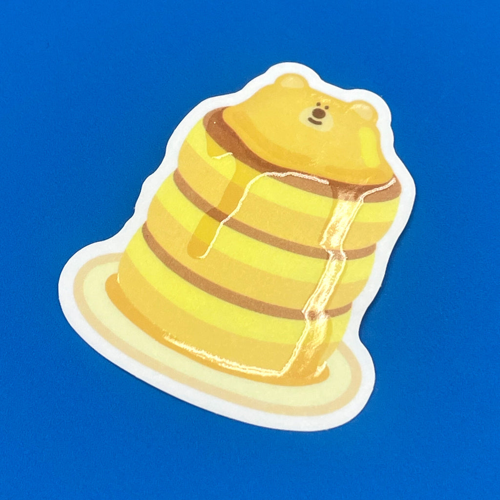 Close up of a bear butter sticker depicting bear on top of a pile of pancakes, with dripping butter, showing the 3D effect.