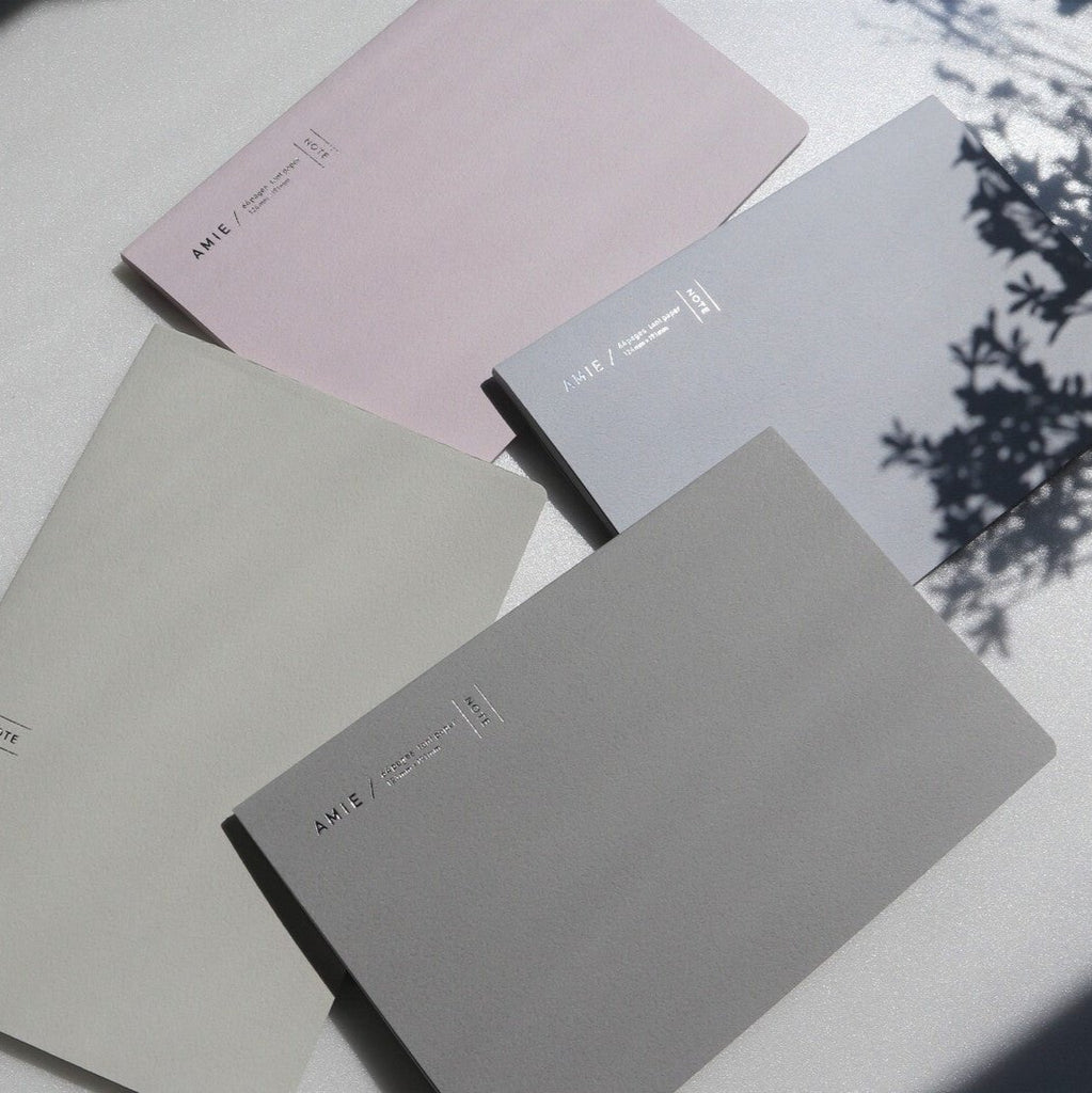 AMIE Nuance Colour Notebook in four colours: Pétales (light pink), Lavande (light purple), Lin (beige), and Coule (grey), with a soft, minimalistic aesthetic.
