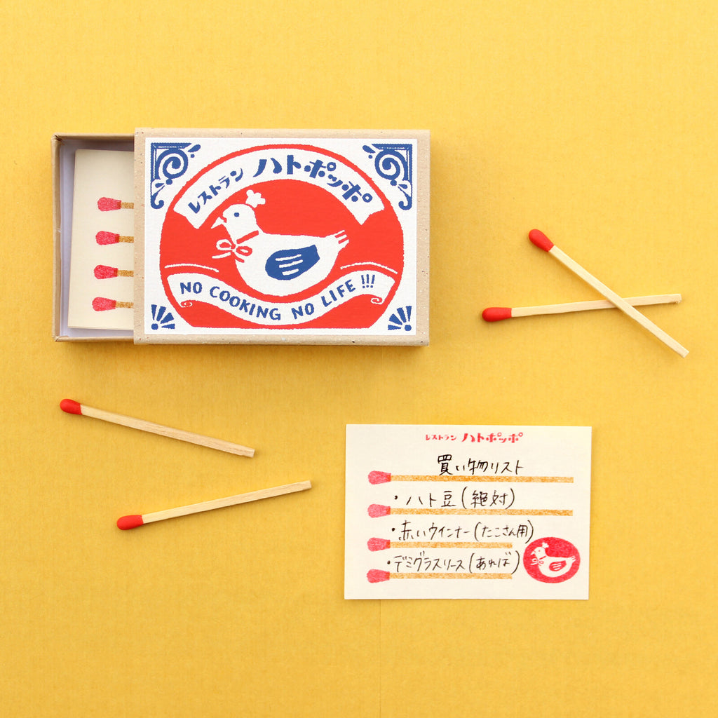 Close-up of matchbox memo with Pigeon Chef design, showing red-tipped matchstick memo sheets
