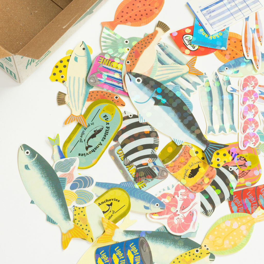 Close-up of seafood-themed flake stickers including fish, shrimp, and canned designs
